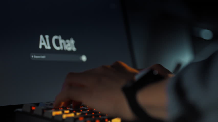 In the evening, a man's hands rapidly type a query into the AI chat interface on the computer monitor, utilizing the keyboard to interact with the model's chat window