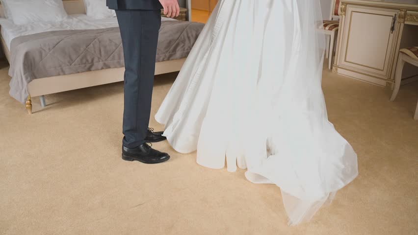 The bride and groom are standing in a hotel room