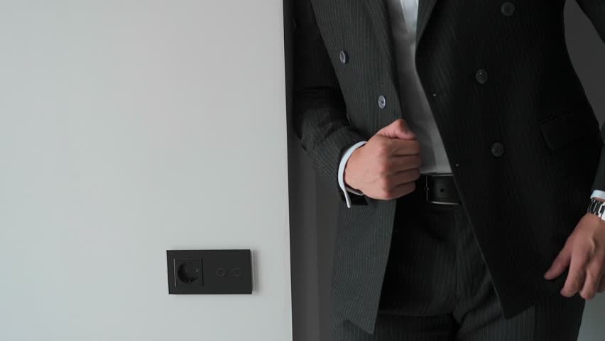 A man buttons his jacket. A businessman is getting ready for a meeting