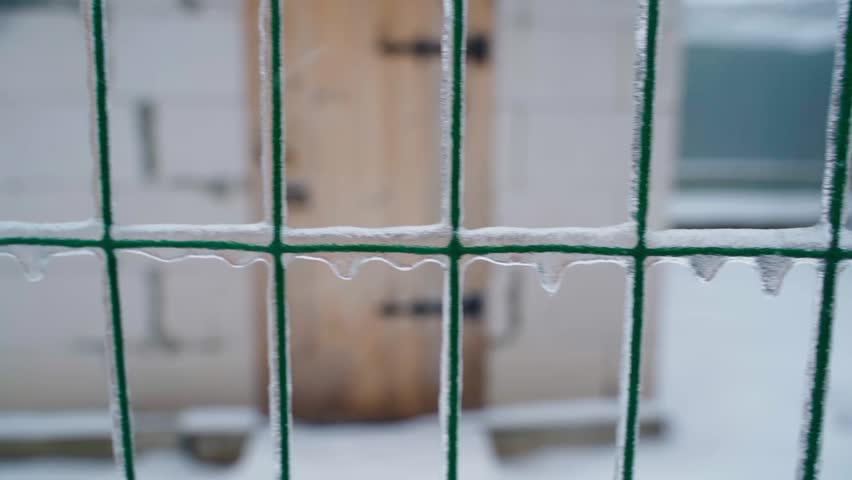 Ice-covered fence mesh close-up during harsh winter