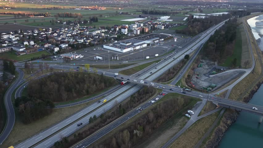 Drone moving sideways over highway interchange and bridge with flowing morning traffic. Transport infrastructure and commuting concept.