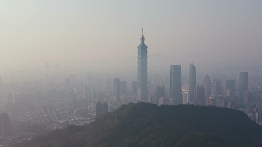 Aerial view from Xiangshan Mountain of Taipei 101 during smoggy sunset, iconic tower piercing thick atmospheric haze, orange skies blending with urban pollution layer, hazy city skyline below.