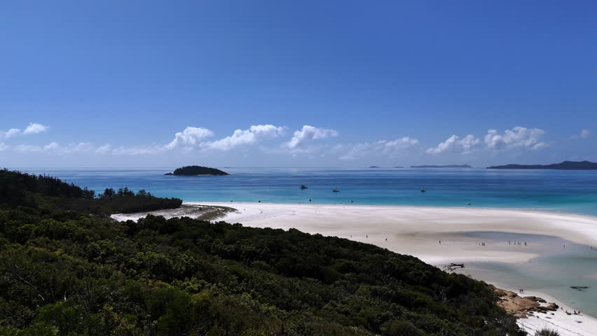 Aerial drone view of stunning tropical coastline with white sand beach and vibrant turquoise waters in the Whitsunday Islands Australia.