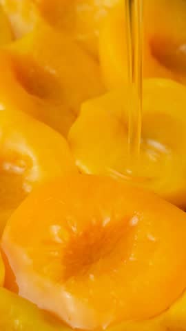 Slow motion of pouring sugar syrup on canned peaches