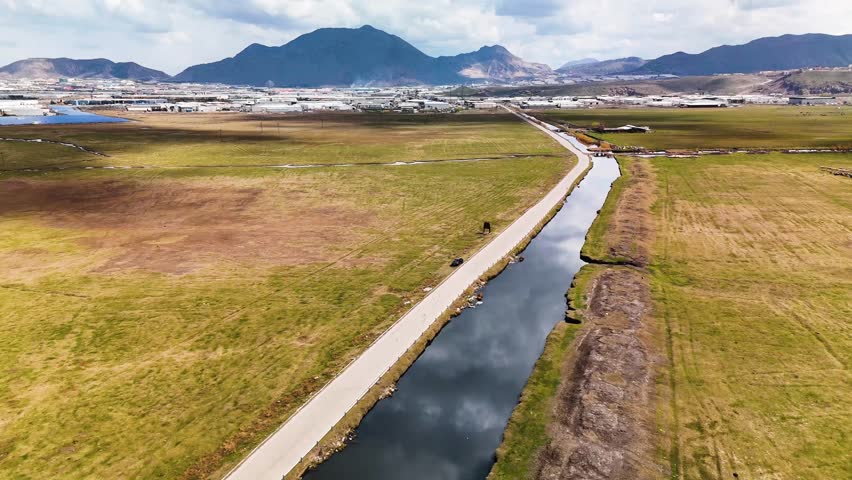 Aerial view gliding over a long concrete irrigation canal in a rural agricultural area