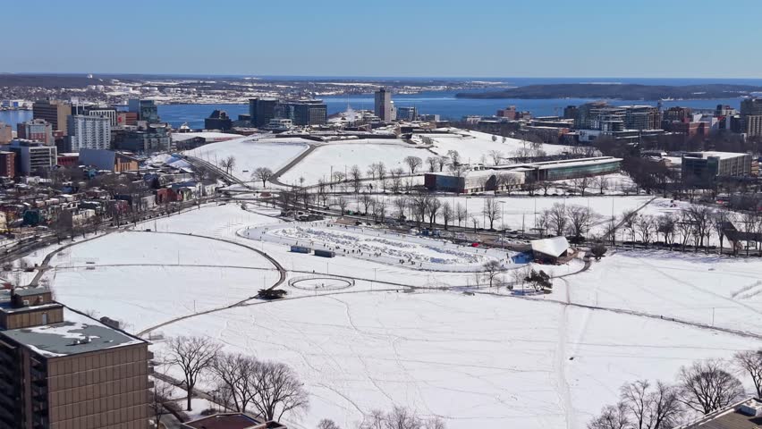 Stunning aerial drone view: people of all ages skating on the bustling Halifax oval rink on a bright sunny November day. Nova Scotia, Canada, perfect winter recreational scene 4K.