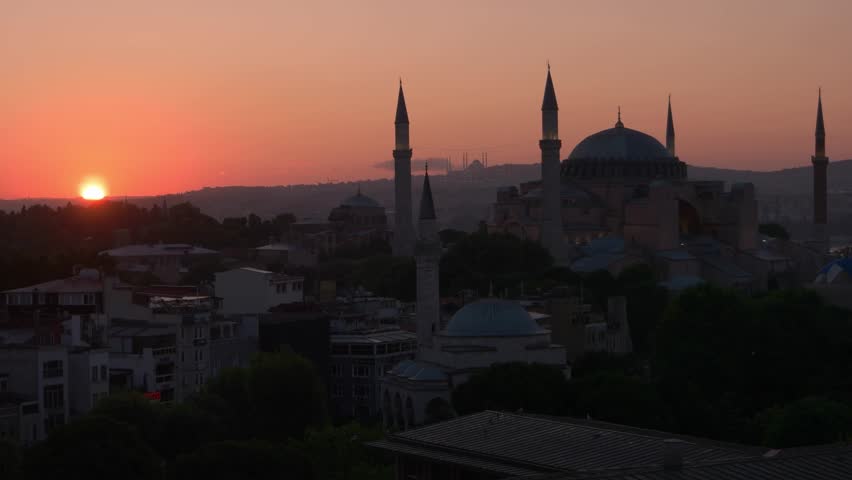 Istanbul, Turkey - 06.25.2023: The historic Hagia Sophia mosque with tall minarets is illuminated by a bright sunrise over Istanbul city. Warm golden light spreads across the skyline, highlighting