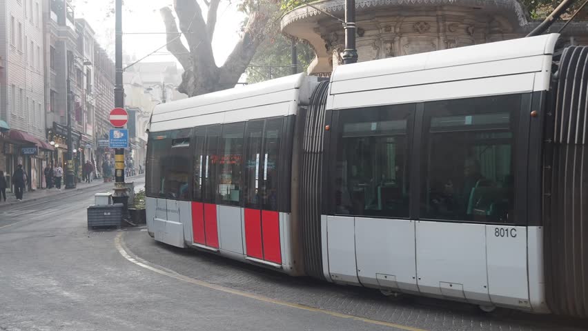 Modern tram driving through historic Istanbul street near sultan ahmet area with pedestrians and electric scooter