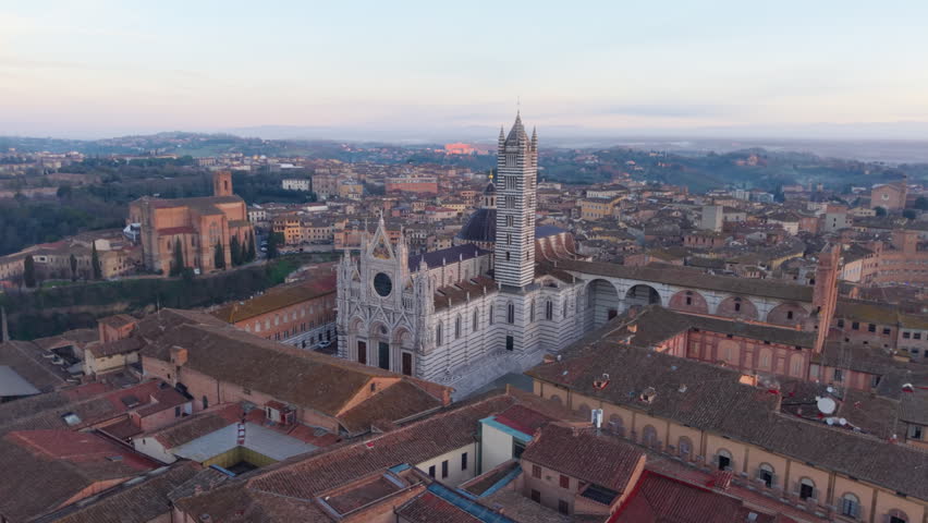 Drone moves toward Siena Cathedral with tilt down revealing facade