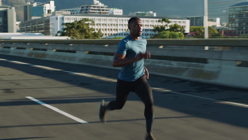 Black man, running and fast on bridge for fitness in city for cardio, training and wellness in summer. African person, outdoor and sprint for speed development, workout and exercise in urban street