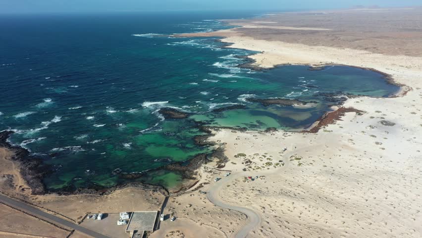 Top-down drone footage capturing the unique landscape of Playa de los Charcos, where turquoise tidal pools contrast with handmade circular stone structures used as wind protection, creating a distinctive coastal scene in the Canary Islands.