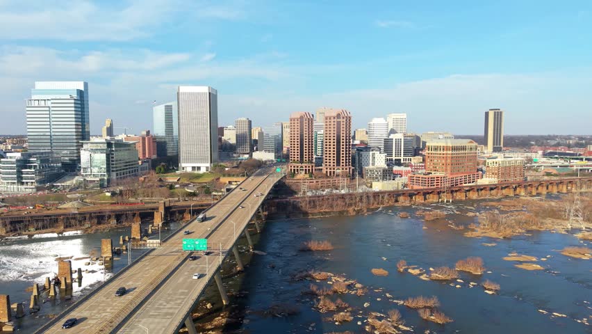 Richmond, Virginia skyline featuring the Manchester Bridge crossing the James River rapids into the downtown financial district. 4k aerial cinematic video.