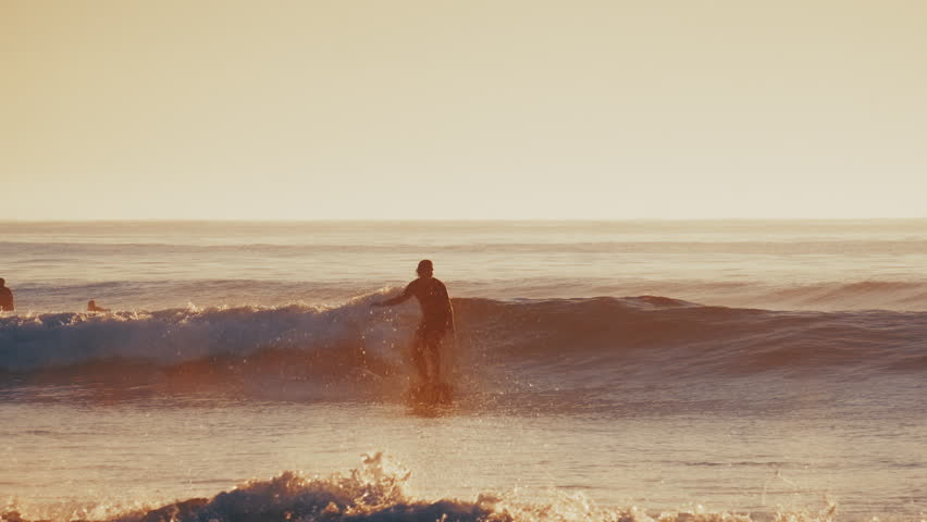 Surfer rides the wave in the ocean during calm sunrise. The Kuril islands, Russia