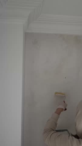Painting wall person. A painter paints a white wall with a roller. High quality 4k footage