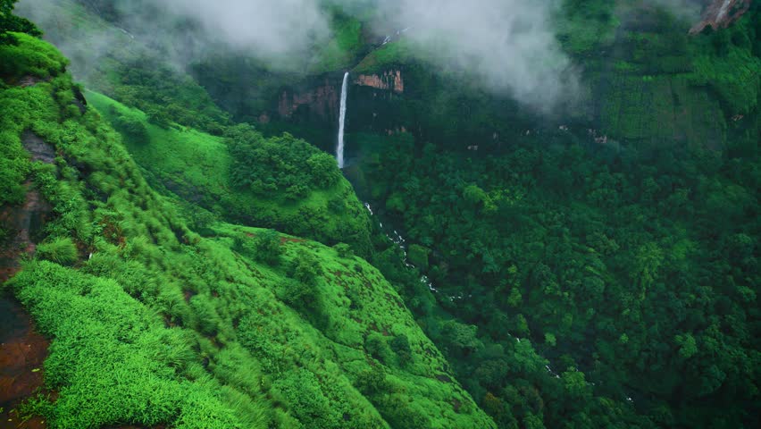 4K Aerial view of Ring waterfall as seen from Savlya Ghat in Sahyadri hills, Maharashtra, India. Drone view of powerful waterfall in lush green forest landscape. Western Ghats covered in clouds during monsoon season.