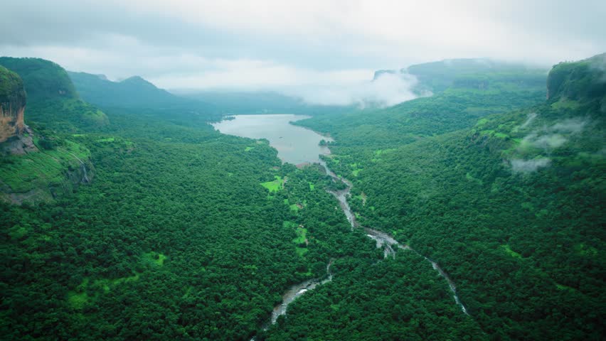4K Aerial view of dark monsoon clouds over green landscape of Sahyadri hills as seen from Savlya Ghat in Maharashtra, India. Scenic view of Lake, rivers and green forest in the Western Ghats.