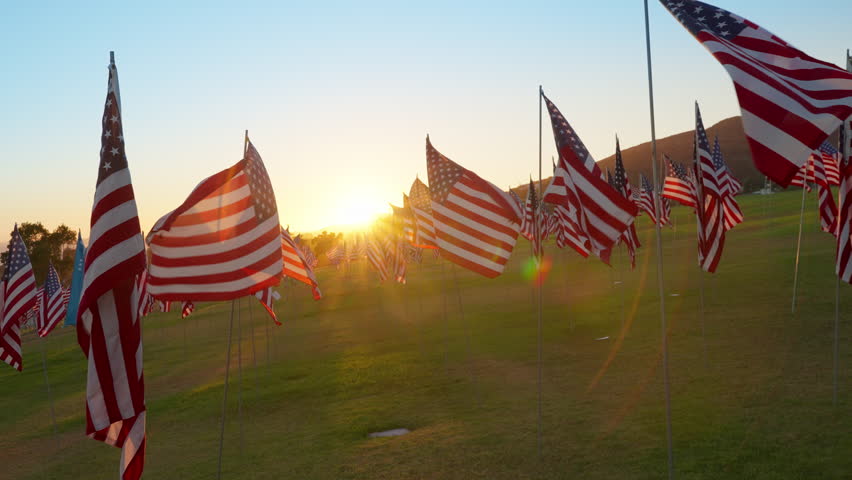 American flag field at sunset in Malibu, California, USA honoring September 11, warm golden light and moving flags creating powerful patriotic and emotional visual scene. Slow motion