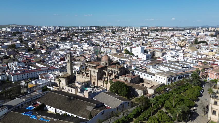 Aerial drone shot moving forward in 4K resolution getting very close to the Jerez Cathedral bell tower and the historic city center during a clear sunny day