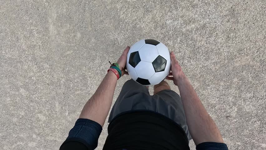 Man performing soccer freestyle tricks, juggling and controlling a football with his feet. First person pov of athletic skill and practice