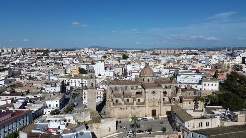 Aerial drone shot moving forward in 4K resolution approaching the Jerez Cathedral bell tower and the old town district under a clear sunny sky