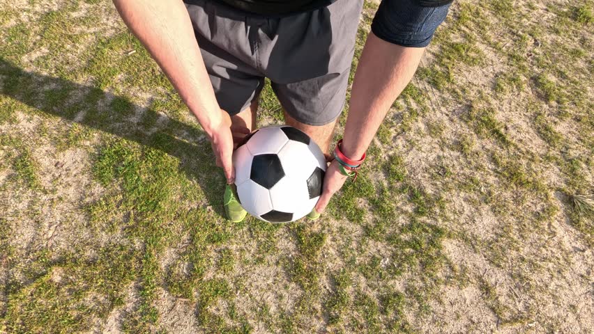 First person view of a skilled football player juggling and performing a trick with a soccer ball on a grass field in slow motion