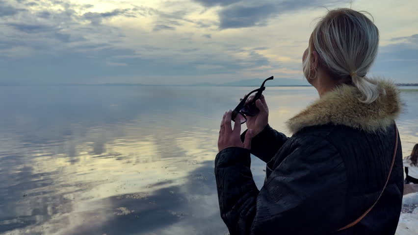 Woman sitting on a boat at sunset, enjoying calm sea and quiet atmosphere. Travel and relaxation lifestyle concept with soft natural light.