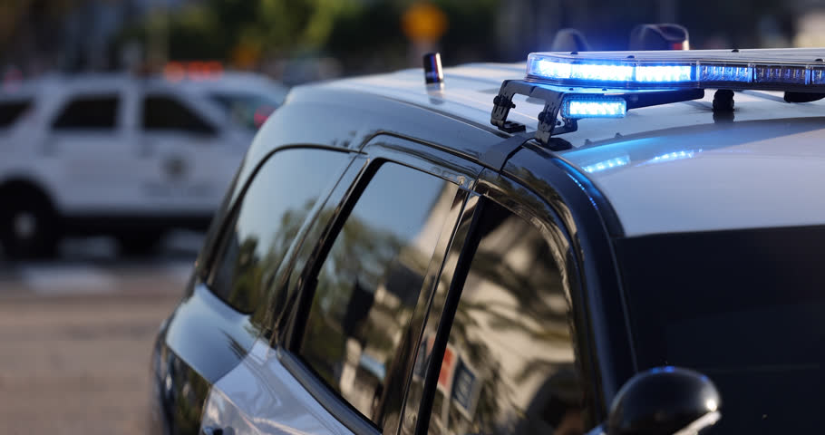 Medium tight side view of flashing blue lights on top of a police car.