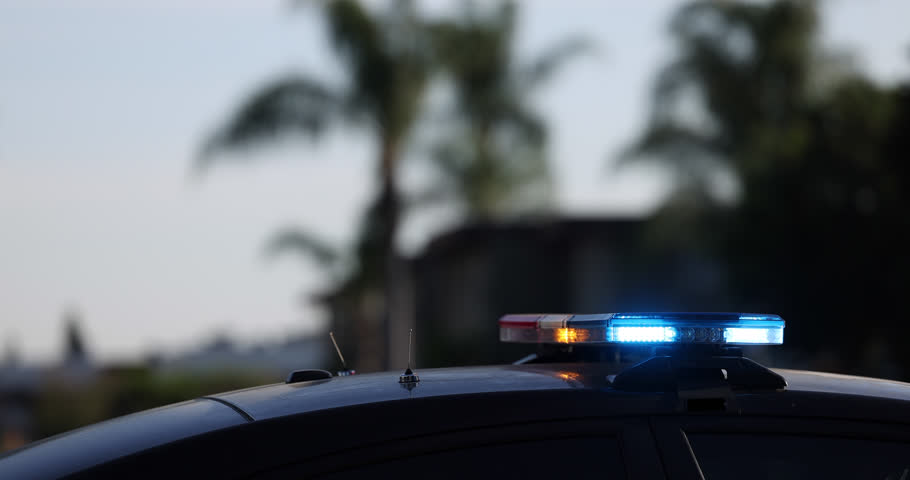 Medium tight side view of flashing blue lights on top of a police car.