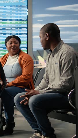 Vertical Video Airport terminal gate, family of three traveling, excited teenager daughter, preparing for boarding plane during family holiday trip. African American travelers with luggage