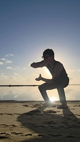 Silhouette of a man playing capoeira on the beach
