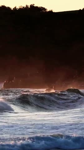 Slow motion close-up of a massive cresting ocean wave breaking with thick white foam.