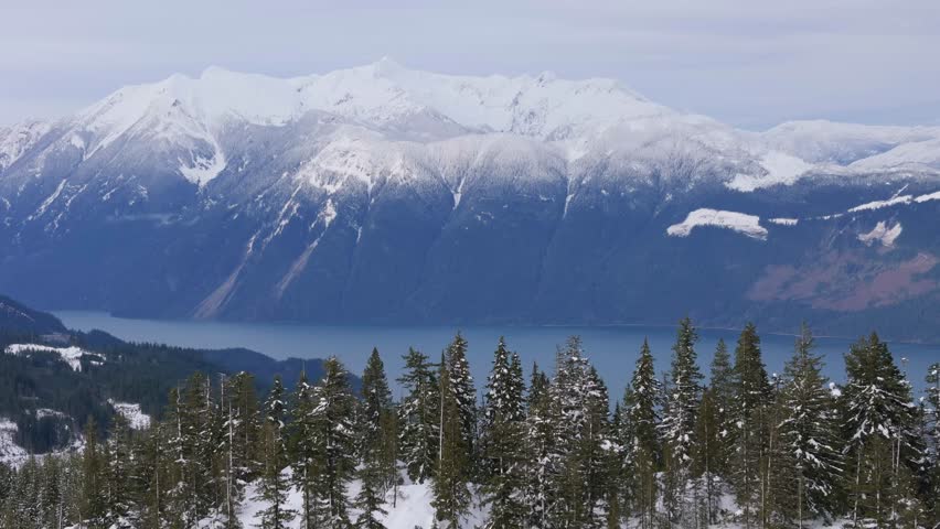 Majestic Winter Landscape in British Columbia Featuring Snow-Capped Mountains, Evergreen Forests, and a Serene Lake