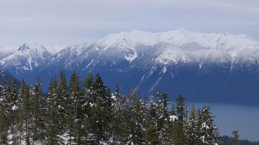 Stunning Winter Landscape of Snow-Capped Mountains, Evergreen Forests, and a Serene Lake in British Columbia, Canada