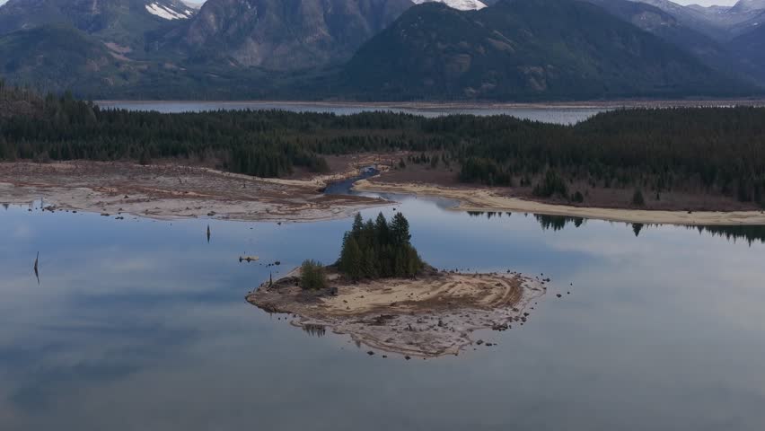 Aerial View of a Serene Lake with a Small Forested Island Amidst Mountains in British Columbia, Canada