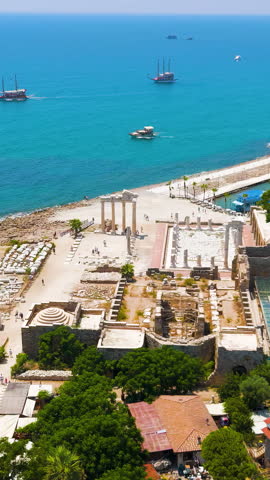 Vertical video. Side, Manavgat, Turkey. Temple of Apollo and Athena under bright summer sun, ancient harbor and South Basilica ruins on Mediterranean coast. Aerial View, Point of interest. Rich colors