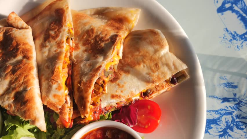 Close-up cinematic footage of delicious quesadillas served with dips and salad