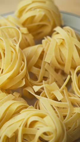 Close up of uncooked tagliatelle pasta coils rotating