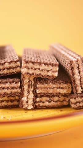 Close up shot of stacked chocolate wafer cookies on yellow plate