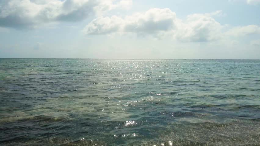 Aerial view of the indian ocean showing a turquoise sea surface with waves and sunlight reflections