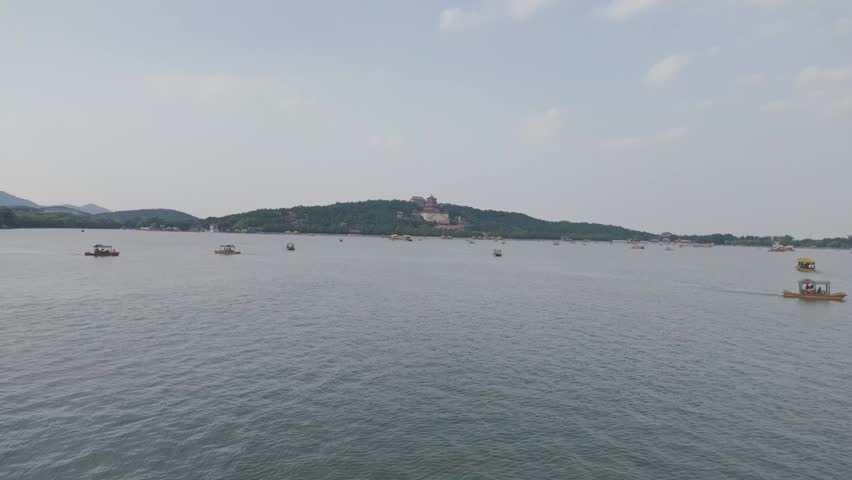 Wide view across Kunming Lake with distant hills at Summer Palace Beijing China, boats cross in water
