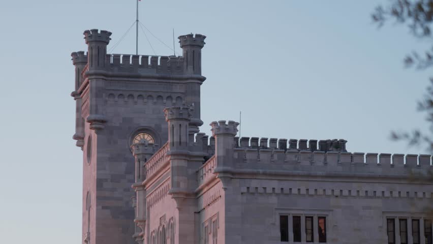 Historical stone towers and battlements of Miramare Castle in Trieste Italy at sunset with warm light reflecting on a stone facade and clear dusk sky beautiful