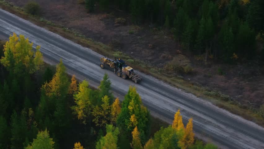 Tractor heavy machinery driving along on highway, vibrant autumn forests and rolling hills of Northwest Montana