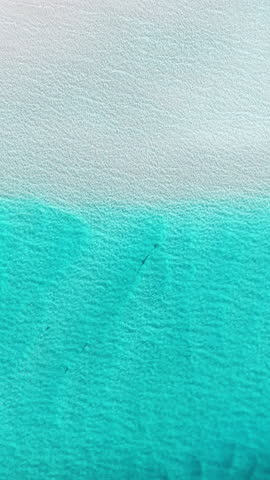 Loopable vertical top down aerial view of La Pelosa beach showing clear turquoise water and white sand in Sardinia