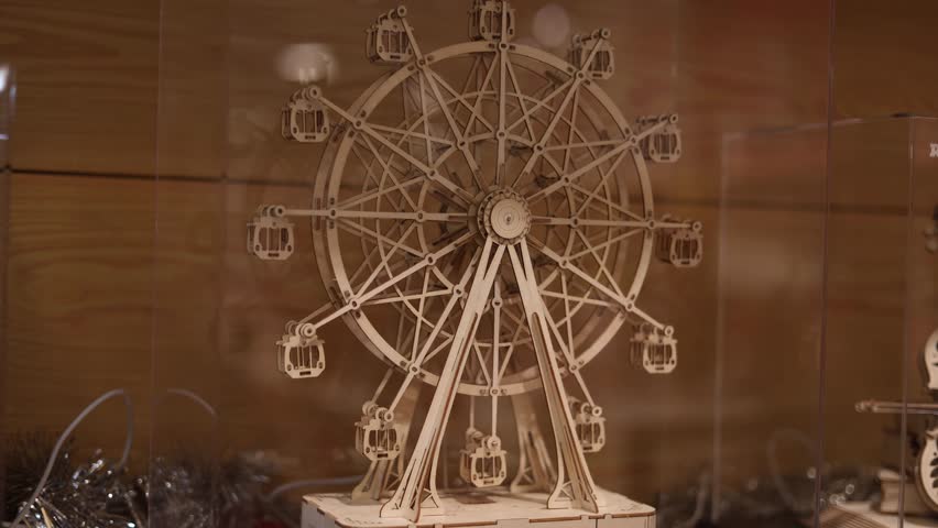 Wooden ferris wheel kinetic model spinning slowly warm light cozy interior decorative mechanism relaxing motion atmospheric scene