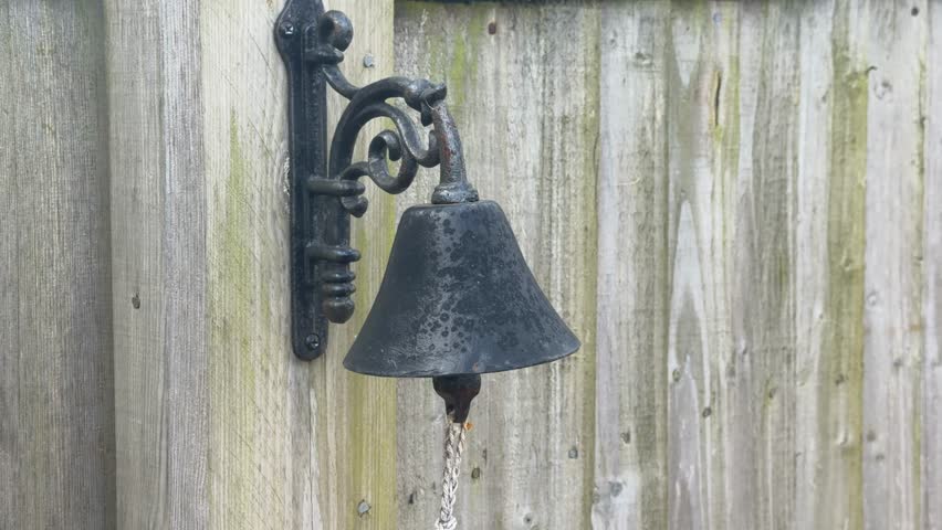 Antique iron bell hanging on fence panning