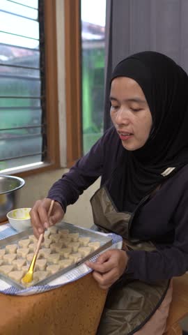 Woman Brushing Egg Wash on Heart-Shaped Cookies Before Baking
