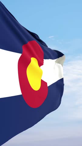 Flag of Colorado waves in slow motion against a blue sky. US State flag Colorado, national symbol, country, union, Colorado government and politics.