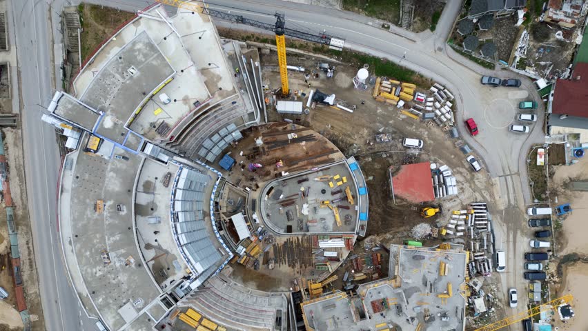 Aerial drone timelapse showing the dynamic construction progress of a large modern hotel with a curved design. Watch floors rise and cranes work as a building site transforms into a completed structure in a compressed timeframe.