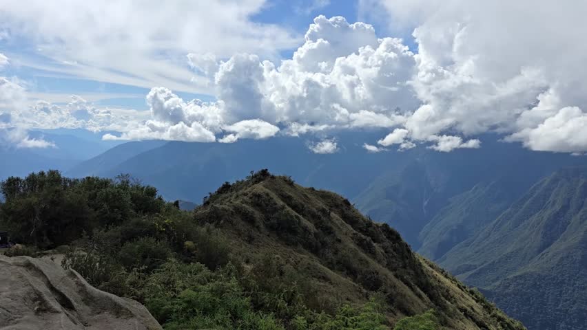 Cusco Region, Peru - 26 June 2024. Clouds hang over rugged Andes mountains along the Inca Trail, covering high peaks while green slopes and rocky ridges remain visible below.