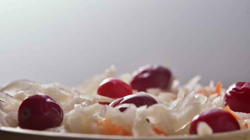 Close up of sauerkraut salad with cranberries and carrot on plate rotating slowly in soft light for healthy food concept